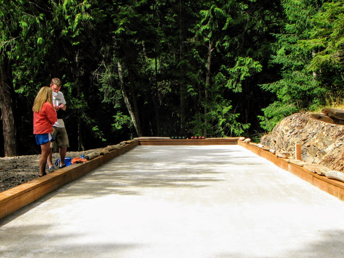 A couple standing on the side of oyster shell surfaced bocce court in San Juan Islands, Washington.